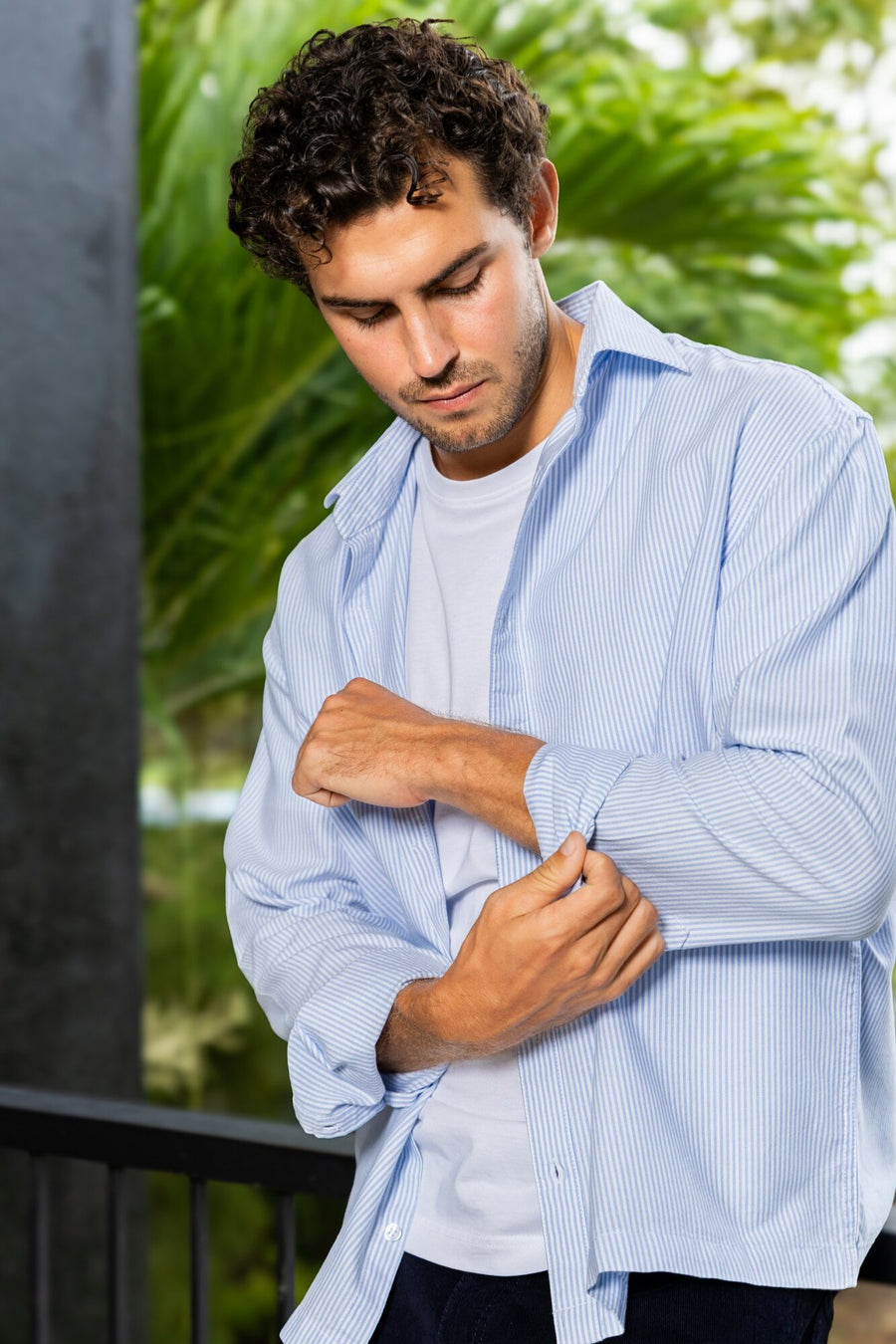 Man rolling the sleeve of a light blue shirt
