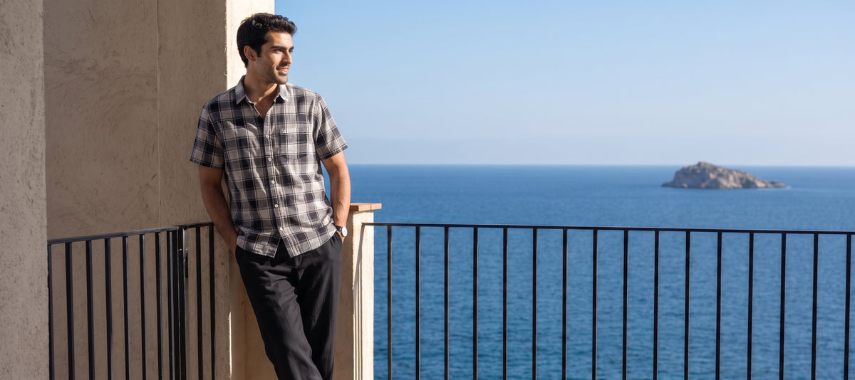 Man in a check short sleeve shirt on a seaside balcony