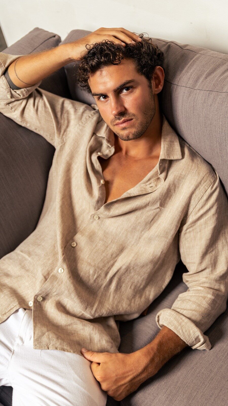 Man in a beige linen shirt resting on a sofa