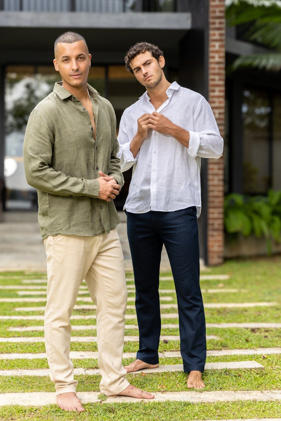 Two men in olive and white linen shirts on a garden lawn