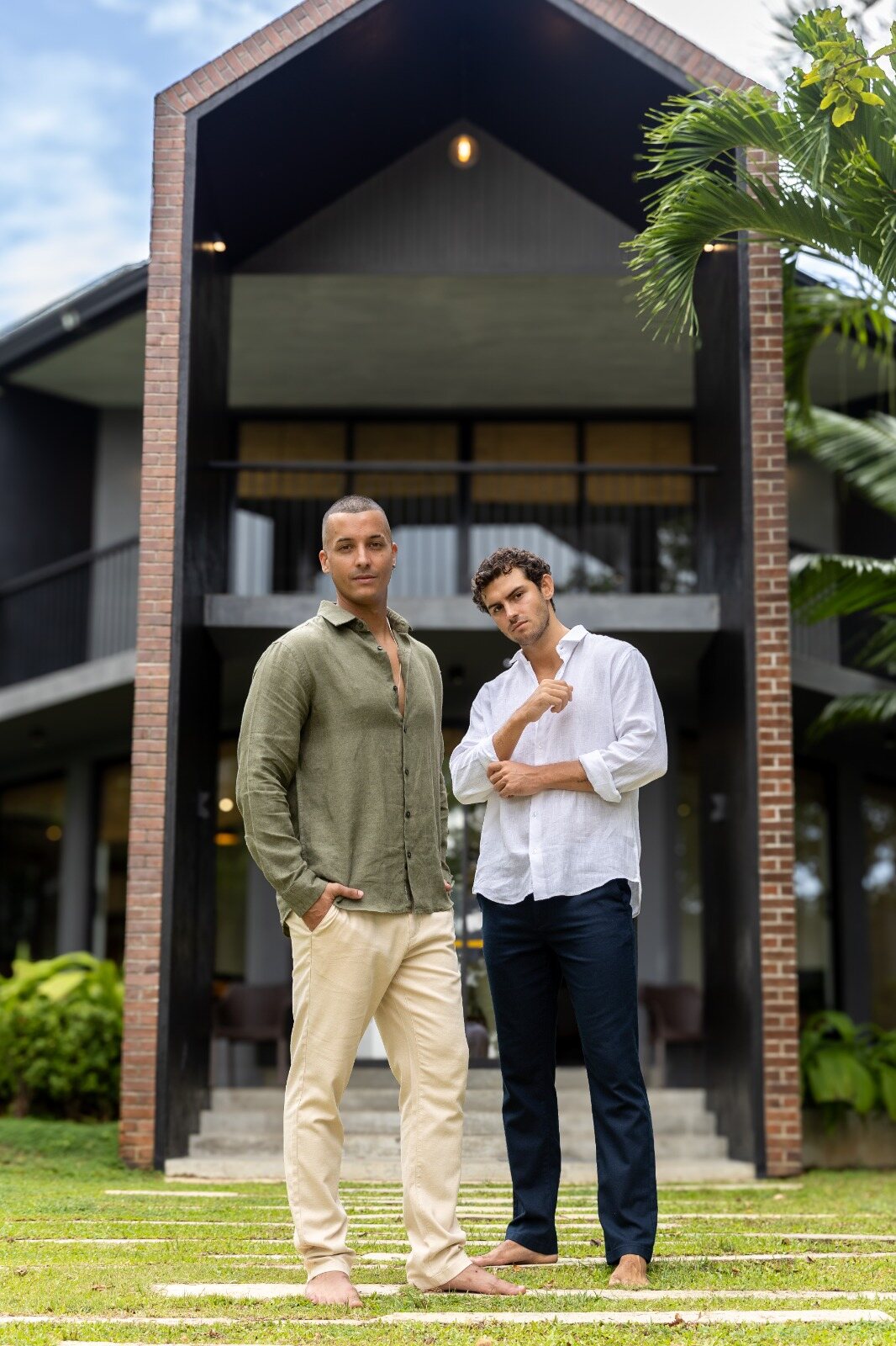 Two men in AnationZ linen shirts in front of a tropical house